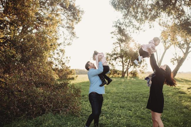 Aunty and uncle flying nieces in the air during Perth family photography session at Perry's Paddock during golden hour