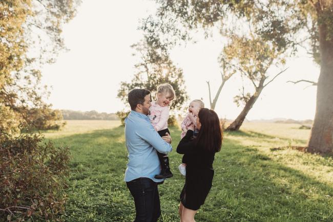 Aunty and uncle holding nieces and laughing during Perth family photography session at Perry's Paddock during golden hour