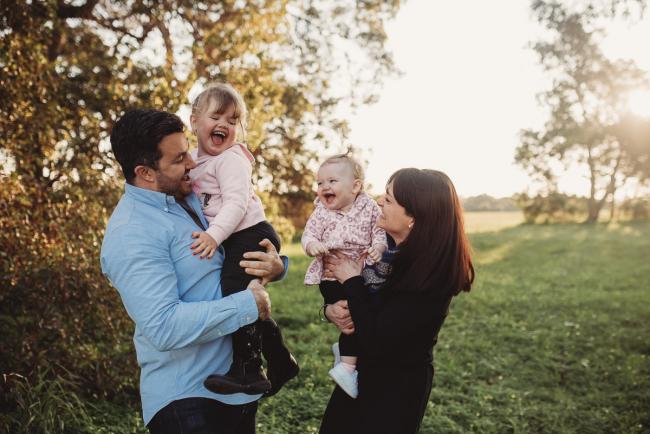 Aunty and uncle holding nieces and laughing during Perth family photography session at Perry's Paddock during golden hour