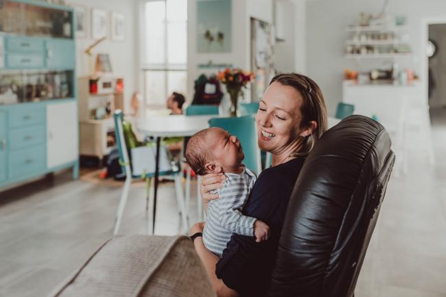 Mother holding new baby on a chair with Lifestyle Newborn Photographer Perth