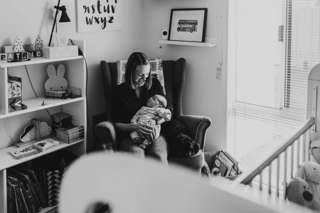black and white image of mother sitting in nursery with baby with Lifestyle Newborn Photographer Perth