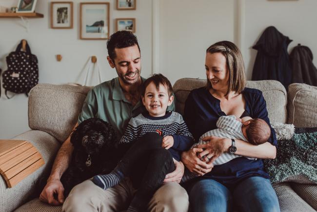 Parents sitting on the couch with their two sons and dog with Lifestyle Newborn Photographer Perth