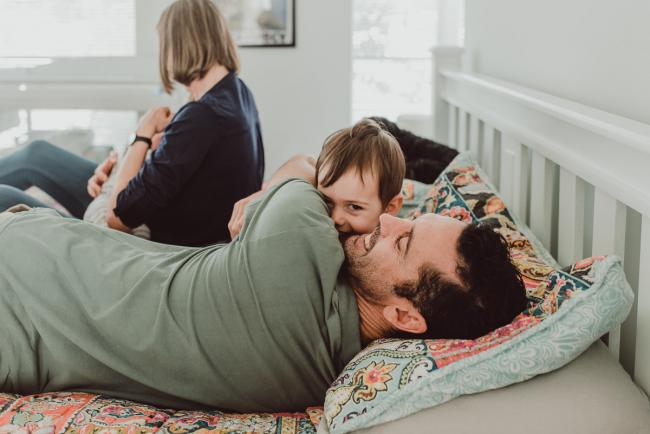 Father and son cuddling on the bed with Lifestyle Newborn Photographer Perth