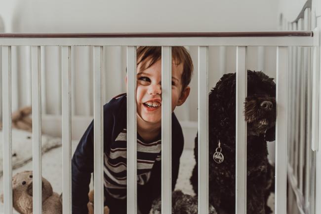 Boy in a cot with his dog with family photographer Perth