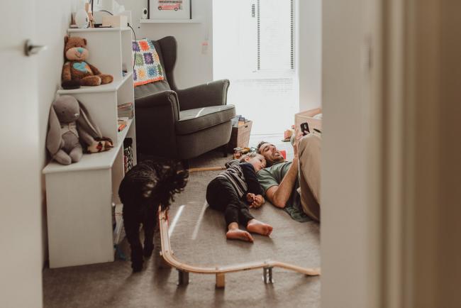 Father and son laying on the floor reading a book with family photographer Perth