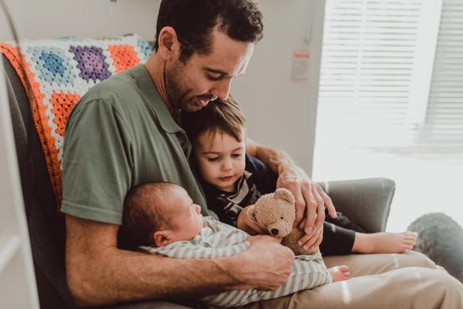 Father sitting with two sons on his lap with Lifestyle Newborn Photographer Perth