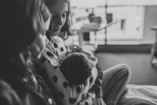 Black and white image of sisters holding their new baby sister with Perth Fresh 48 Photographer at SJOG Mt Lawley