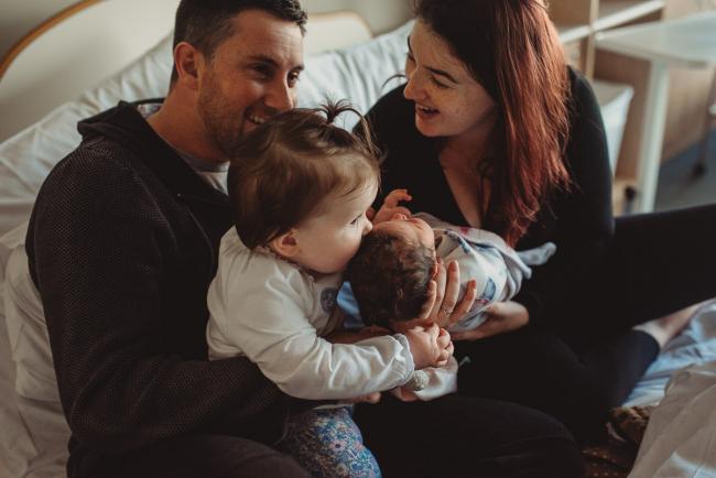 Newborn-and-Fresh-48-Photographer-Perth-SJOG-Mt-Lawley-2-of-51 Girl kissing her baby sister while on parents laps with Perth Fresh 48 photographer at SJOG Mt Lawley