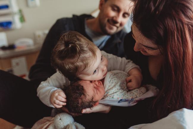 Little girl leaning her head on her new baby sister with Perth Fresh 48 Photographer at SJOG Mt Lawley