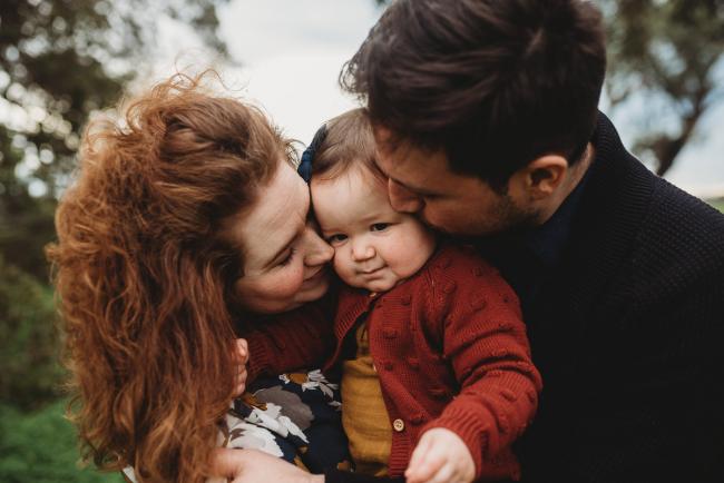 Parents kissing baby daughter with Perth family photographer at Perry's Paddock