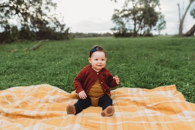 Little girl sitting on a blanket with Perth family photographer at Perry's Paddock