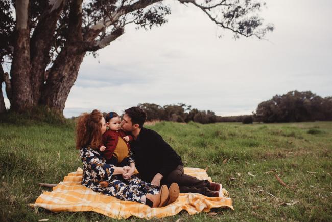 Parents sitting under a tree with their daughter with Perth family photographer at Perry's Paddock