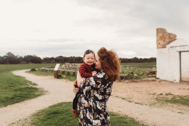 Mother holding baby who is smiling with Perth family photographer at Perry's Paddock