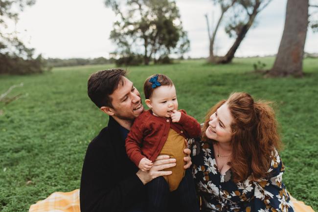 Parents sitting on the grass with their daughter with Perth family photographer at Perry's Paddock