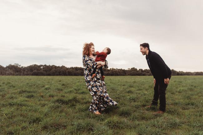Mother spinning around with baby daughter as father laughs with Perth family photographer at Perry's Paddock