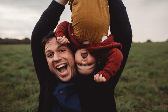 Father's face next to daughter who is upside down with Perth family photographer at Perry's Paddock
