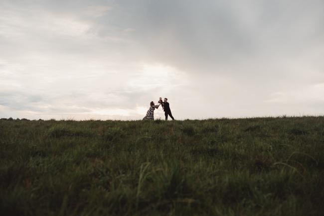 Silhouette image of father lifting baby daughter and mother leaning over to catch her with Perth family photographer at Perry's Paddock