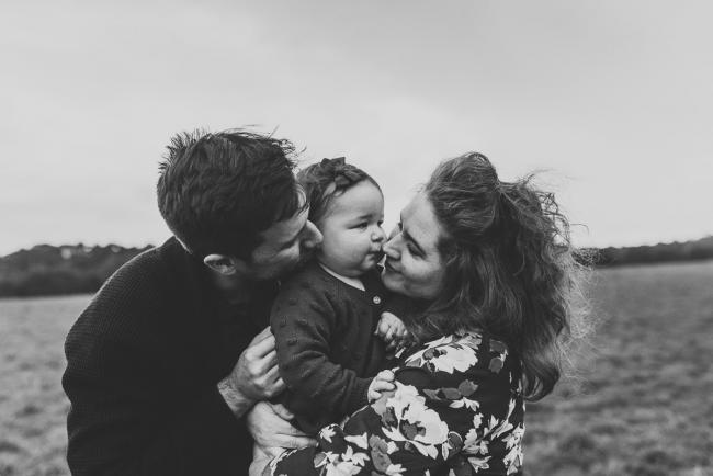 Black and white image of parents kissing daughter with Perth family photographer at Perry's Paddock