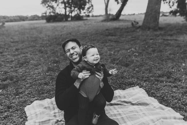 Black and white image of father and daughter laughing with Perth family photographer at Perry's Paddock