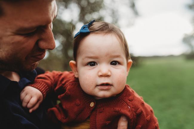 Little girl looking at the camera as father holds her with Perth family photographer at Perry's Paddock