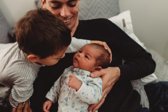 Little boy touching the head of his new baby brother with lifestyle newborn photographer Perth