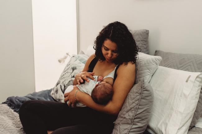 Mother breastfeeding baby on the bed with lifestyle newborn photographer Perth