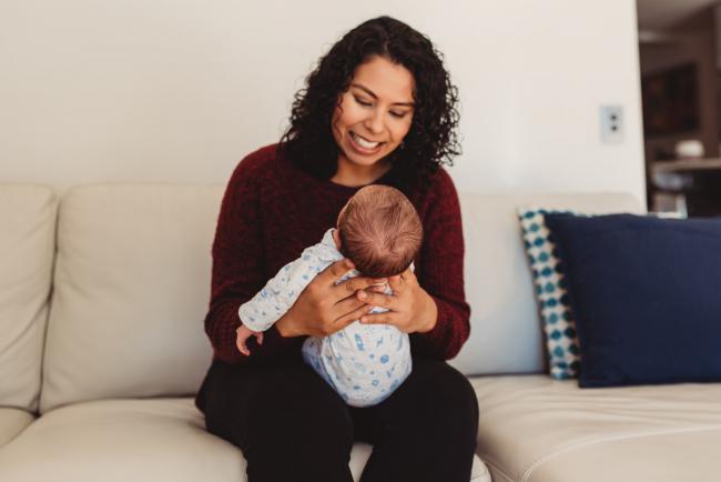 Mother smiling down at her new baby with lifestyle newborn photographer Perth