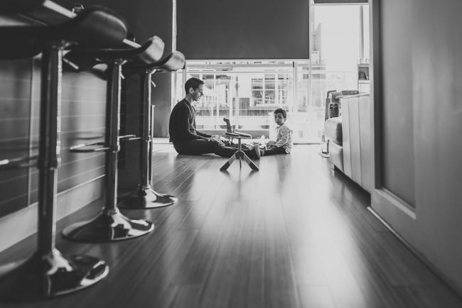 Black and white image of father and son on the floor with lifestyle newborn photographer Perth