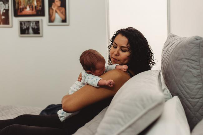 Mother holding baby on her shoulder with lifestyle newborn photographer Perth