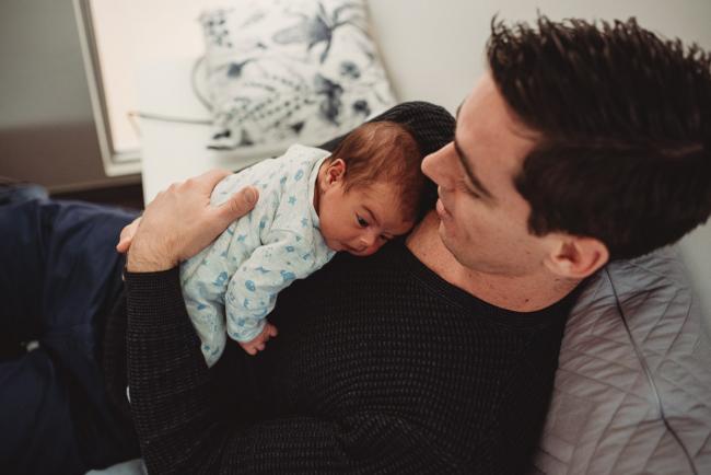Baby laying on father's chest with lifestyle newborn photographer Perth