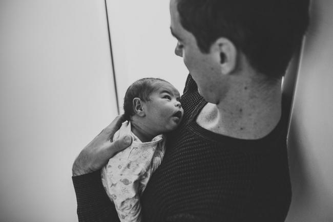 Black and white image of baby on father's chest with lifestyle newborn photographer Perth