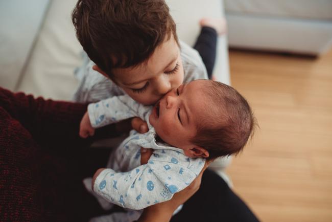 Little boy kissing baby brother with lifestyle newborn photographer Perth