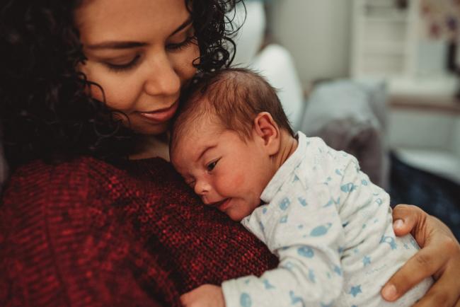 Mother cuddling new baby with lifestyle newborn photographer Perth