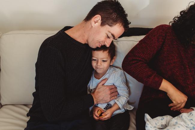 Father and son cuddling on the couch with lifestyle newborn photographer Perth