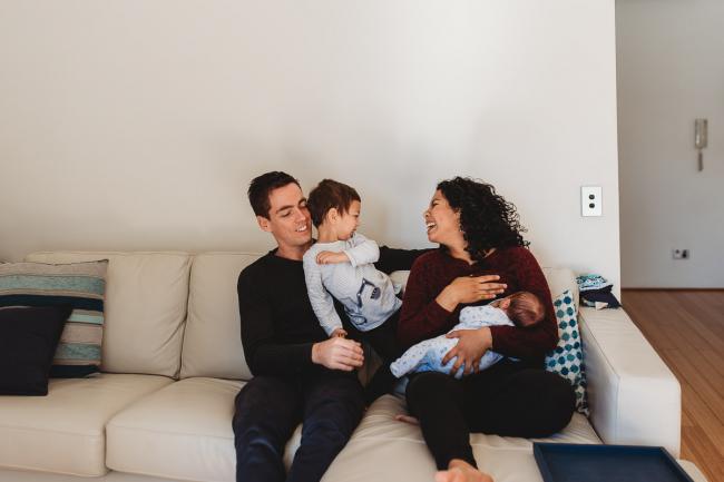 Family of four sitting on the couch with lifestyle newborn photographer Perth