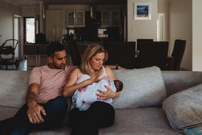 Perth-Newborn-Photographer-1-of-60 mother and father sitting on the couch with baby daughter with Perth newborn lifestyle photographer