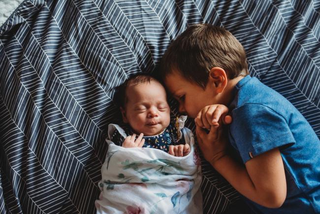 Little boy cuddling in next to his baby sister with Perth newborn lifestyle photographer