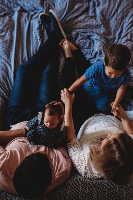 Top down image of father holding new baby and mother holding older son with Perth newborn lifestyle photographer