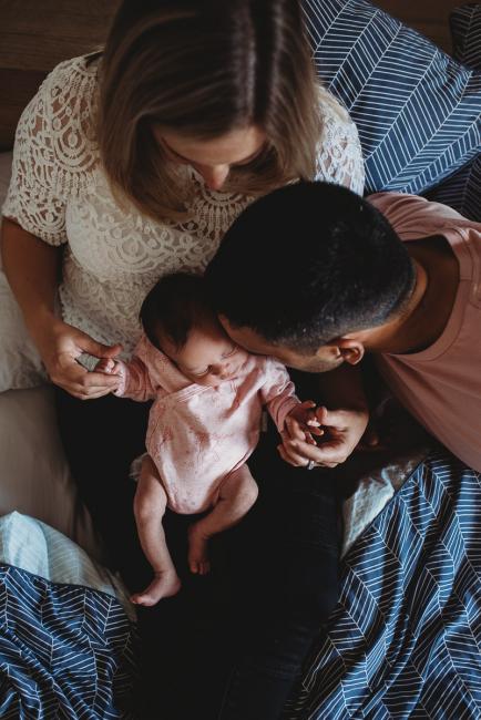 Perth-Newborn-Photographer-29-of-60 Mother holding new baby on her lap while dad kisses baby with Perth newborn lifestyle photographer