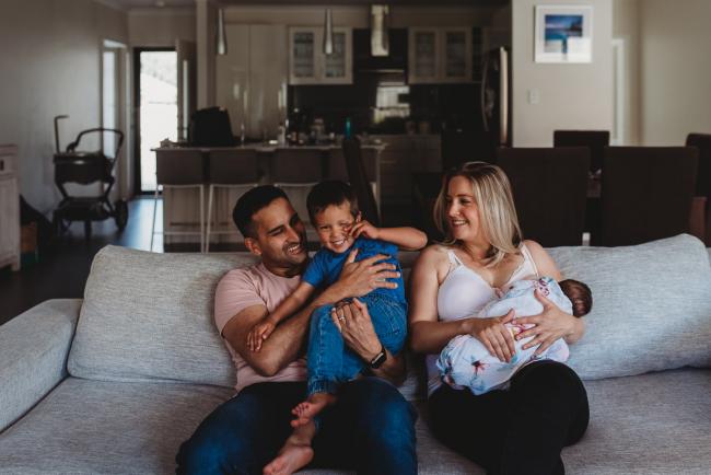 Perth-Newborn-Photographer-3-of-60 Family of four sitting on the couch laughing with Perth newborn lifestyle photographer