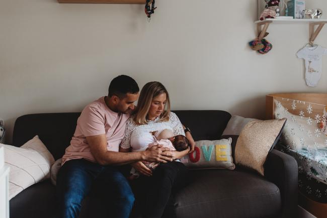 Perth-Newborn-Photographer-34-of-60 Parents sitting on couch with newborn baby with Perth newborn lifestyle photographer