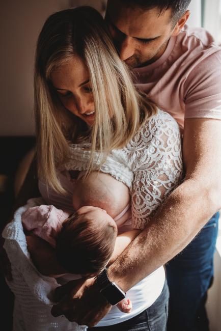 Perth-Newborn-Photographer-38-of-60 Mother breastfeeding newborn baby as father embraces them with Perth newborn lifestyle photographer