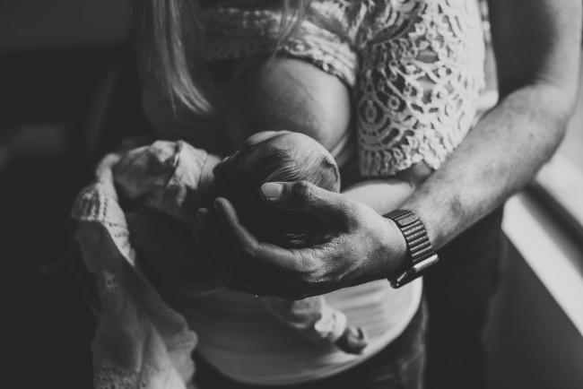 Perth-Newborn-Photographer-39-of-60 Black and white image of newborn baby breastfeeding while dad cradles her head with Perth newborn lifestyle photographer