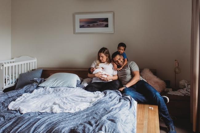 Perth-Newborn-Photographer-42-of-60 Parents sitting on bed with newborn and toddler with Perth newborn lifestyle photographer