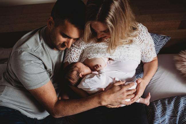 Mother breastfeeding as father hugs them with Perth newborn lifestyle photographer