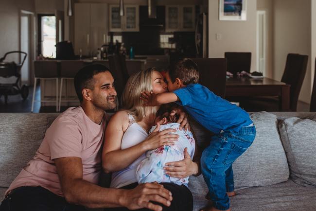 Perth-Newborn-Photographer-7-of-60 Little boy kissing mother who is holding baby sister and sitting next to father with Perth newborn lifestyle photographer