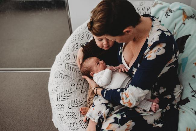 Mother sitting on a chair with her toddler and newborn baby with Perth newborn lifestyle photographer
