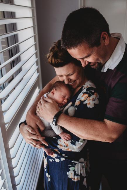 Parents holding newborn baby with Perth newborn lifestyle photographer
