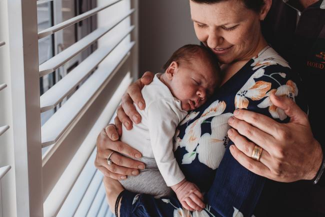 Mother holding newborn baby with Perth newborn lifestyle photographer