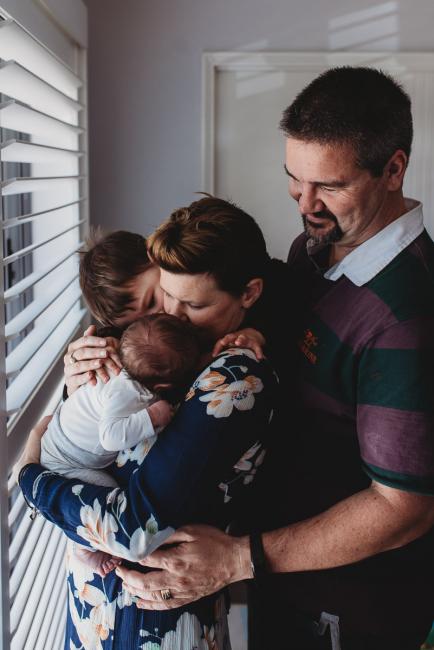Parents and big brother around newborn baby with Perth newborn lifestyle photographer